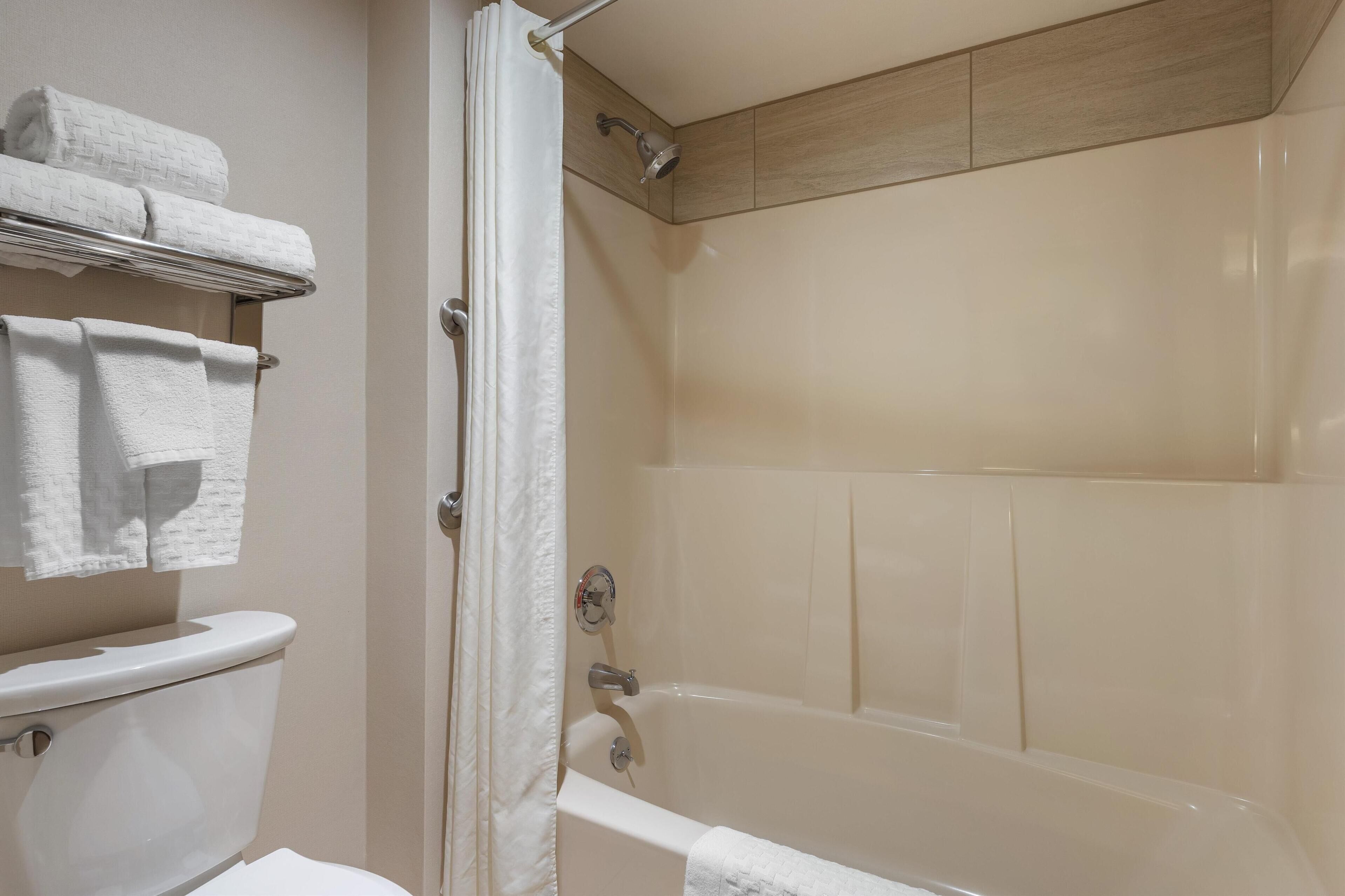 Un baño con bañera, inodoro y perchero para toallas.