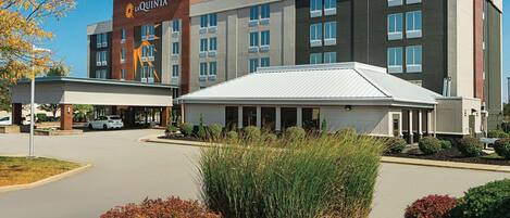 A hotel with a modern design, featuring a prominent entrance and a covered parking area.