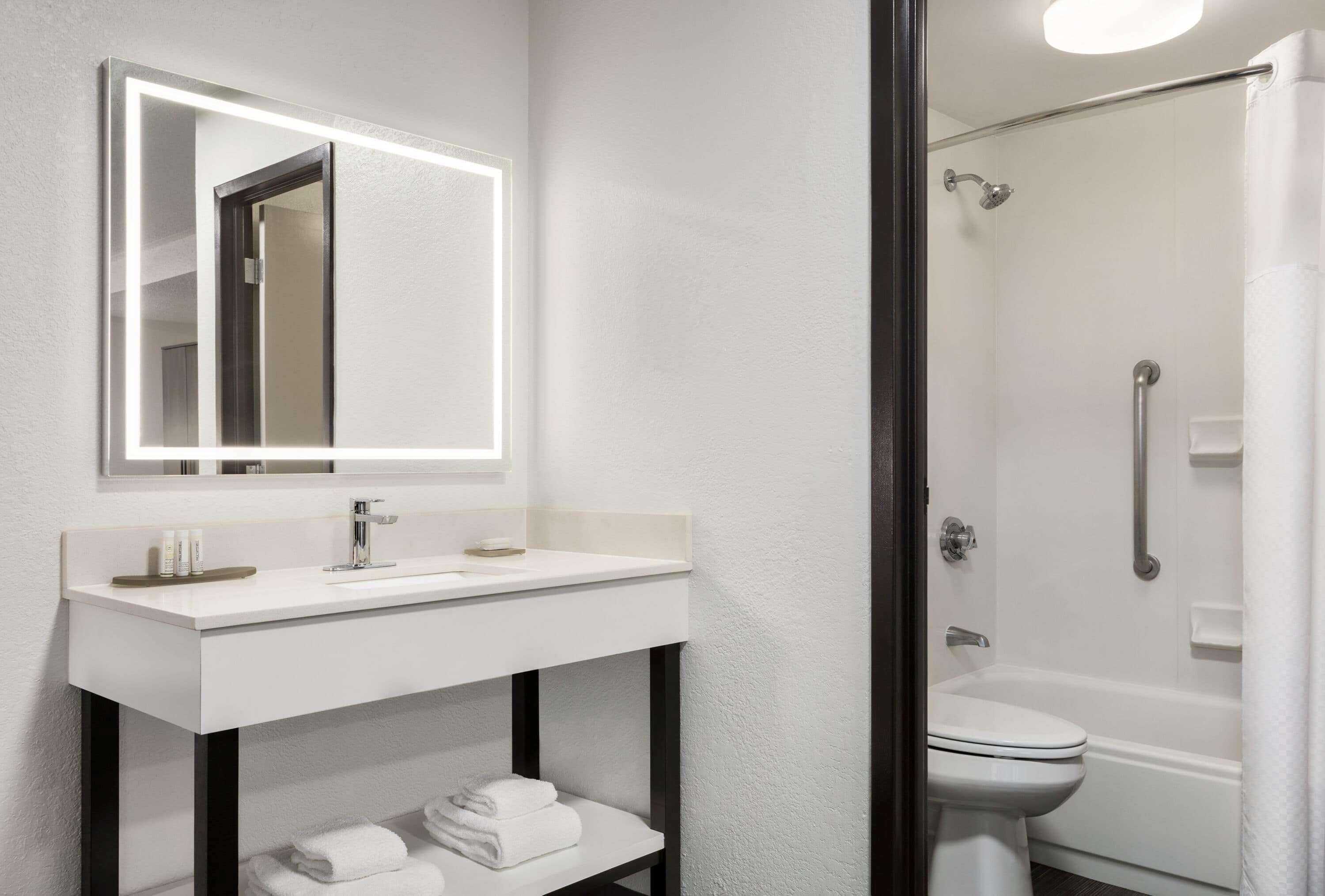 A modern bathroom with a white sink, mirror, and shower.