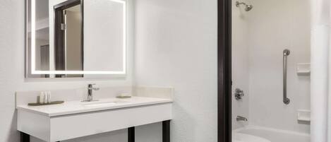 A modern bathroom with a white sink, mirror, and shower.