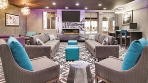 Un espacio lounge moderno con sofás, chimenea y una pantalla de televisión grande.