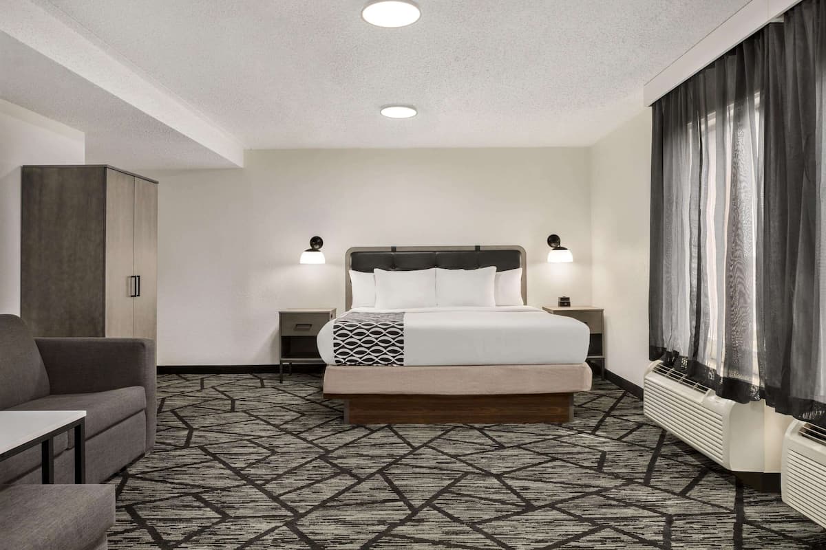 Habitación de hotel con cama, dos mesitas de noche, un escritorio, un sofá y una alfombra estampada.