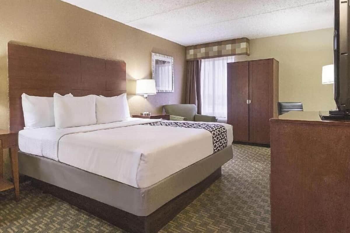 Una habitación de hotel con una cama grande, un escritorio, una silla, un armario y un televisor.