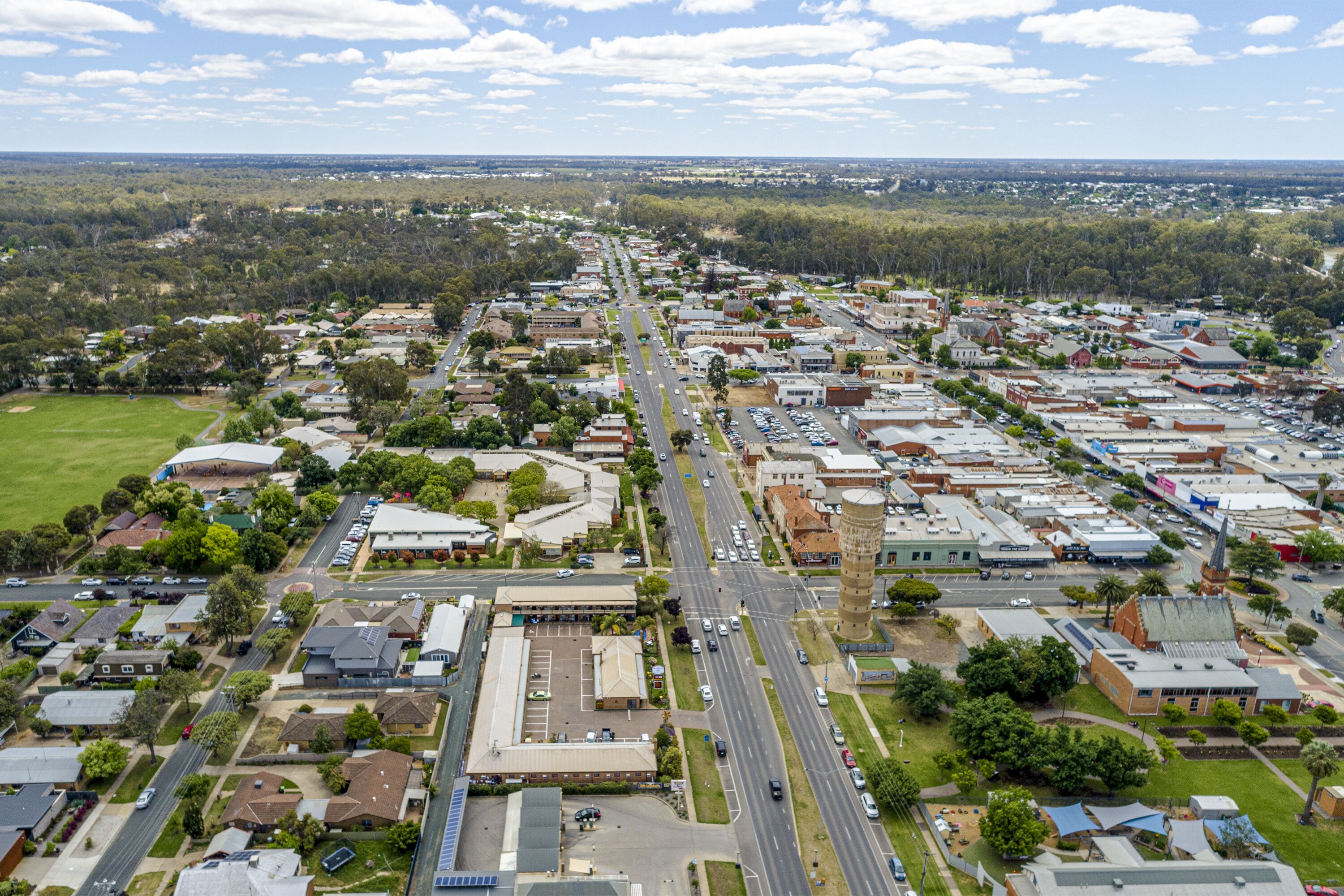 An aerial view of a residential area with streets, houses, and a central road.