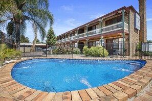 Un hotel con piscina, un edificio de dos pisos y un balcón.