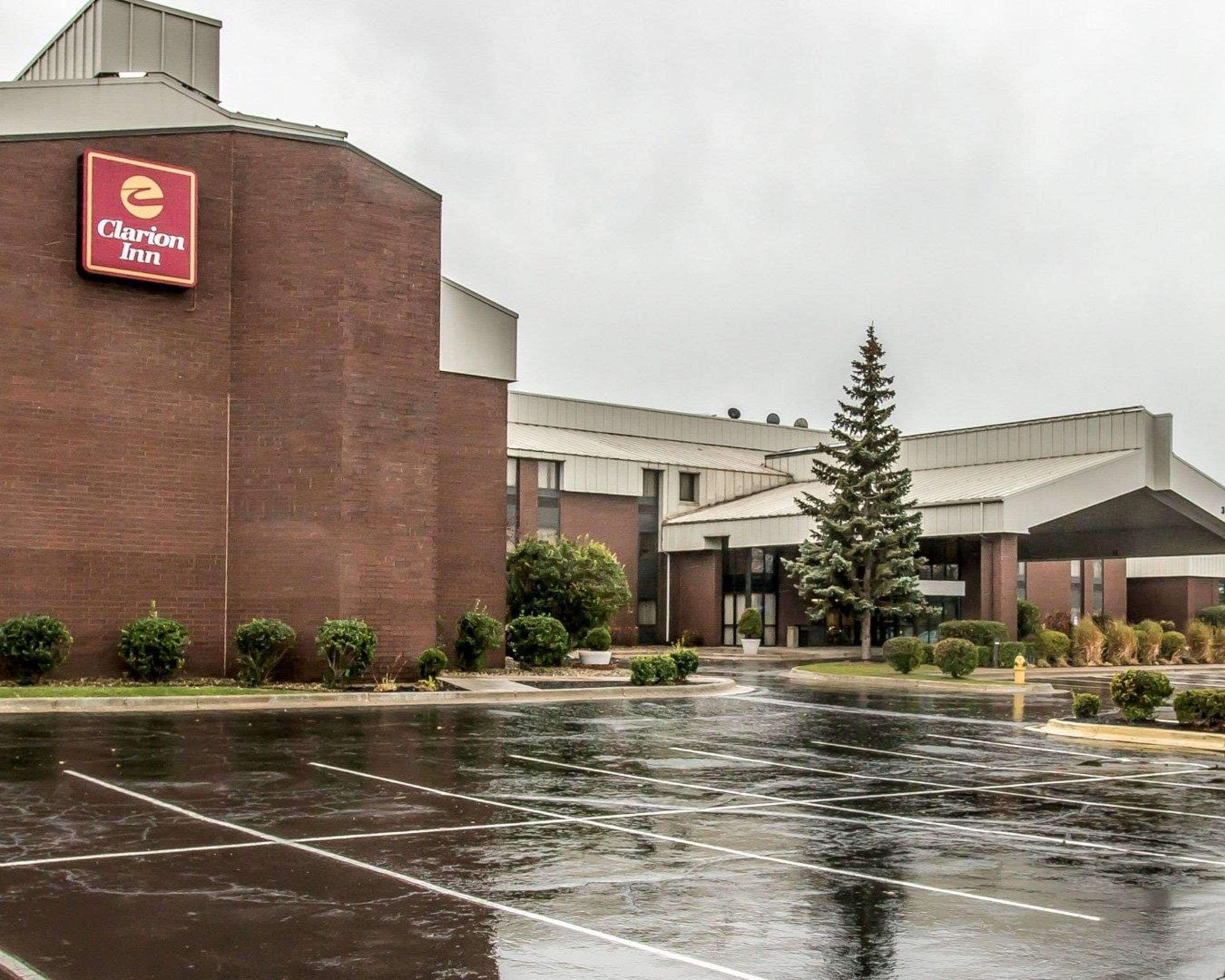 A hotel with a brick facade, a parking lot, and a large evergreen tree.