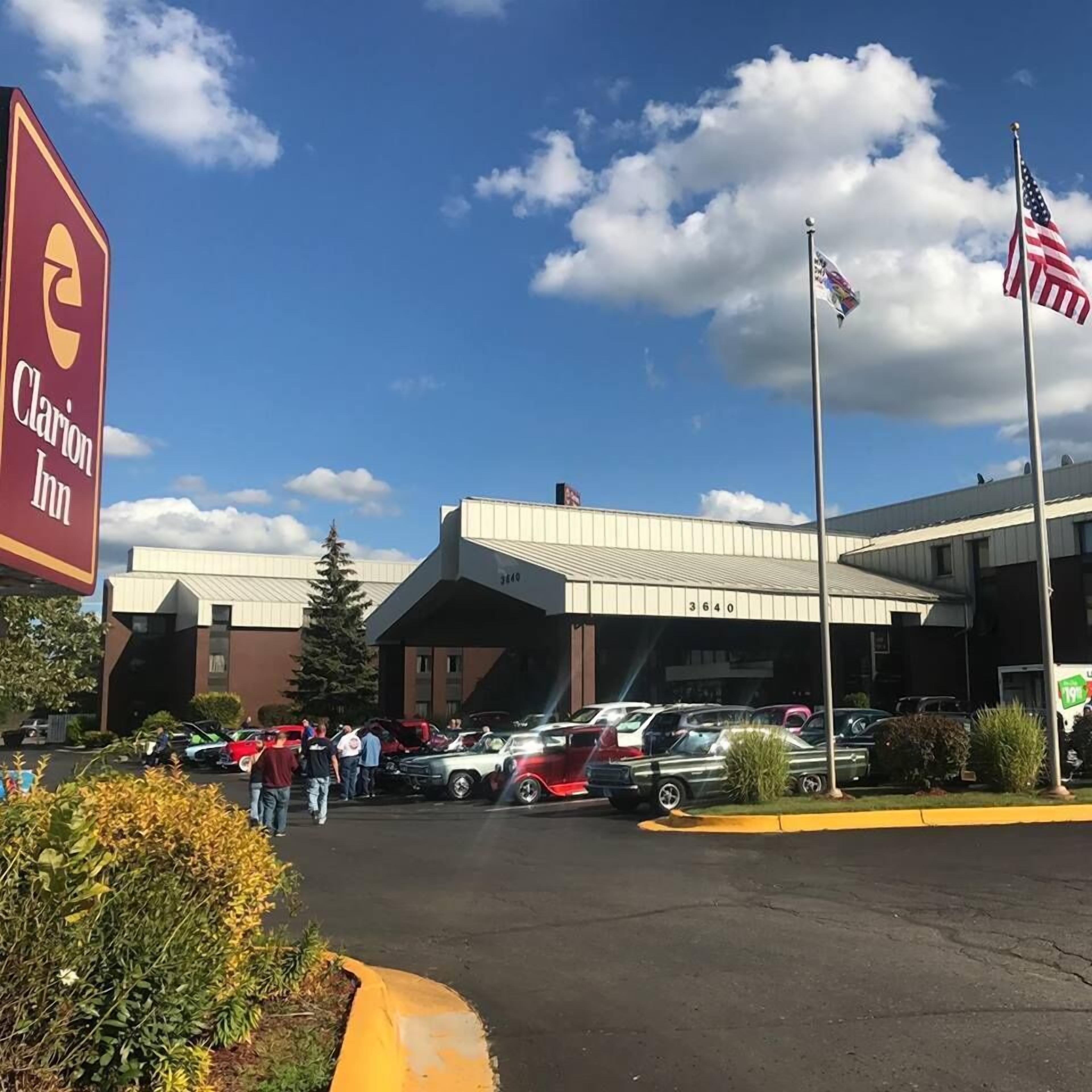 Un hotel con estacionamiento, un cartel de Clarion Inn y una bandera estadounidense.
