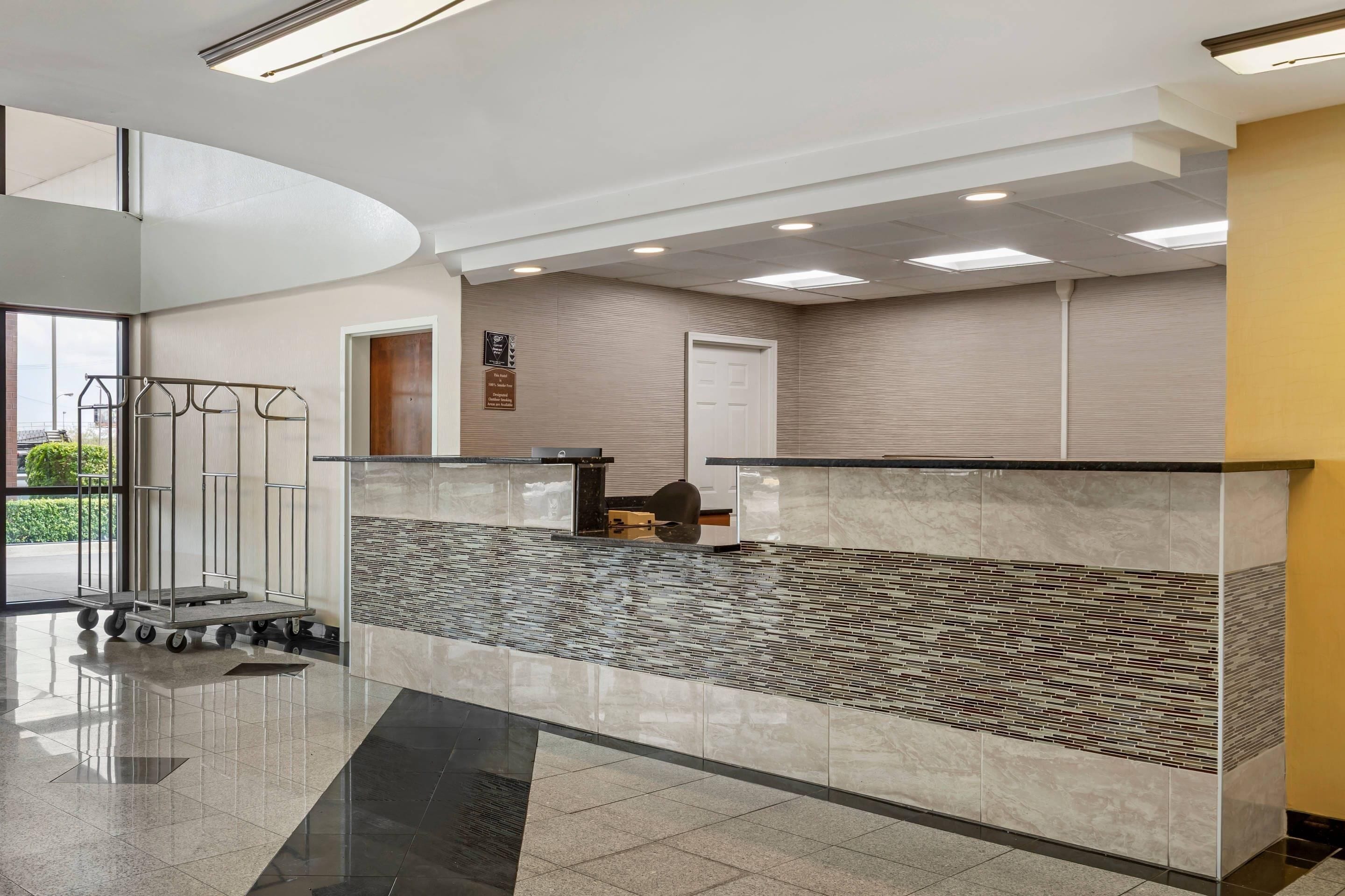 Un área de recepción moderna con mostrador, zona de espera y vistas al exterior.