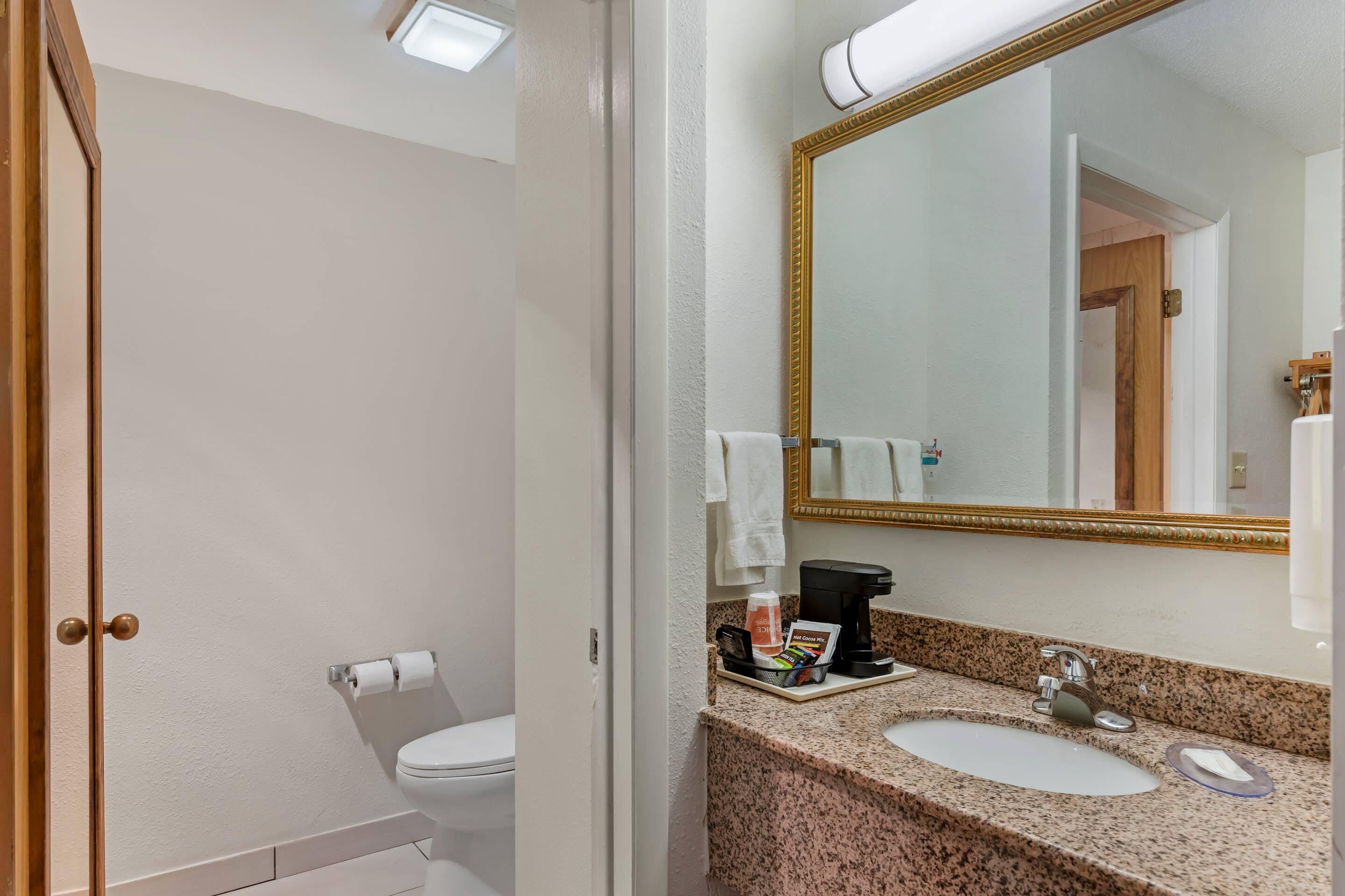 A bathroom with a toilet, sink, and mirror.