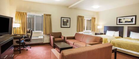 A hotel room with a sofa, a bed, a desk with a chair, a TV, and two bedside tables.