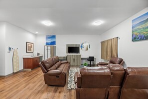A modern living room with leather sofas, a flat-screen TV, and a kitchen area with a microwave. - Days Inn by Wyndham Seattle Aurora (Shoreline)