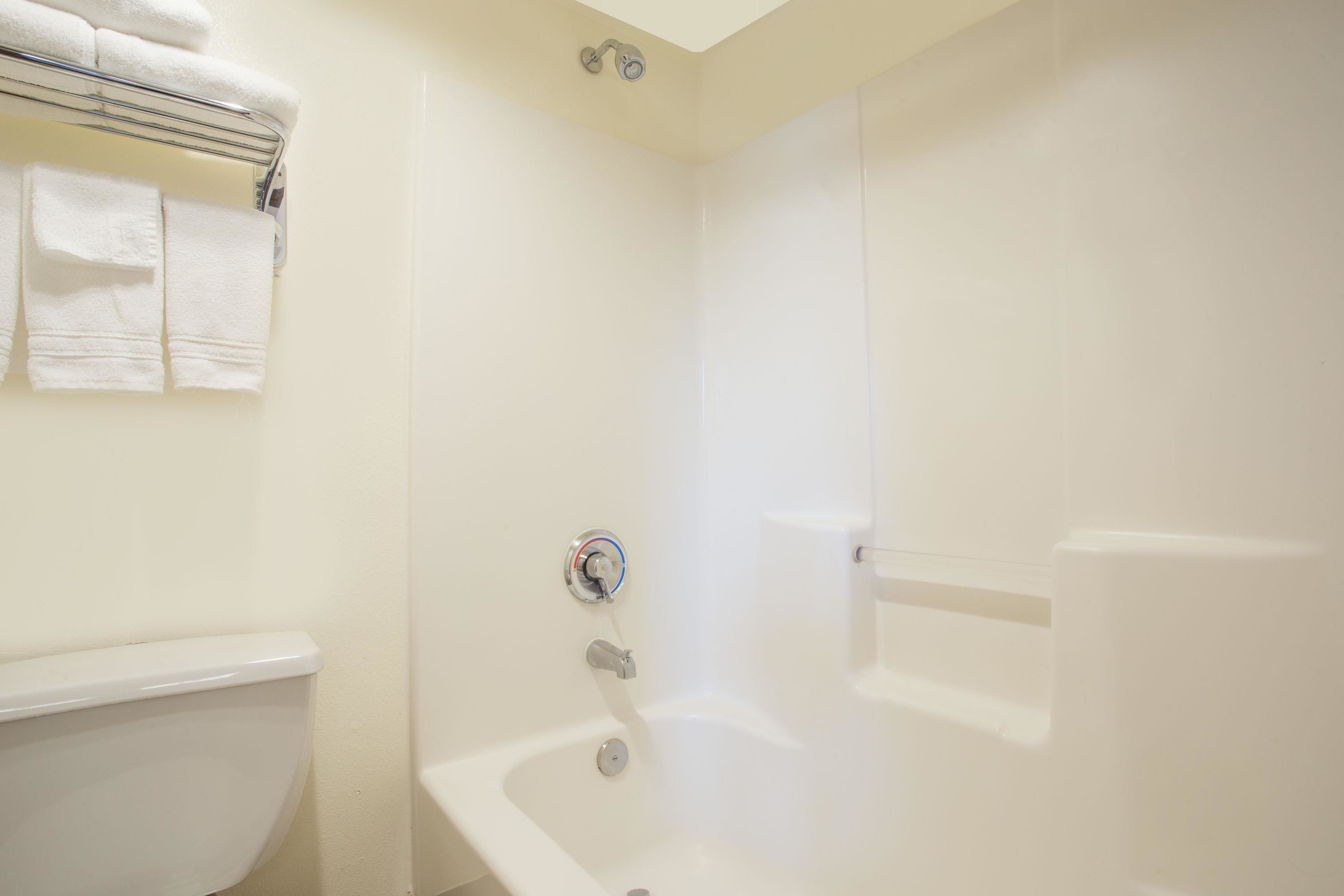 Baño con una bañera blanca, un inodoro y un perchero con toallas.