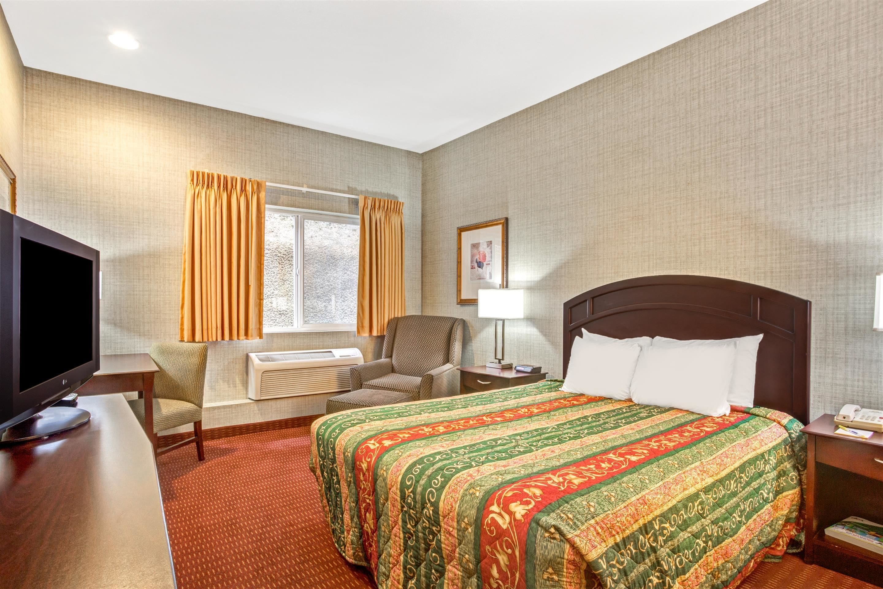 A hotel room with a large bed, a television, a desk, and a chair.