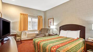 A hotel room with a large bed, a television, a desk, and a chair.