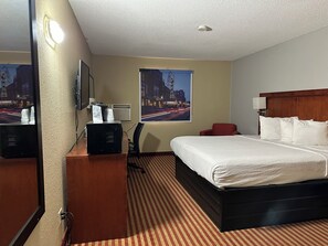 A hotel room with a bed, a desk with a computer, a chair, a mirror, and two posters on the wall. - Americas Best Value Inn Fargo (Fargo)