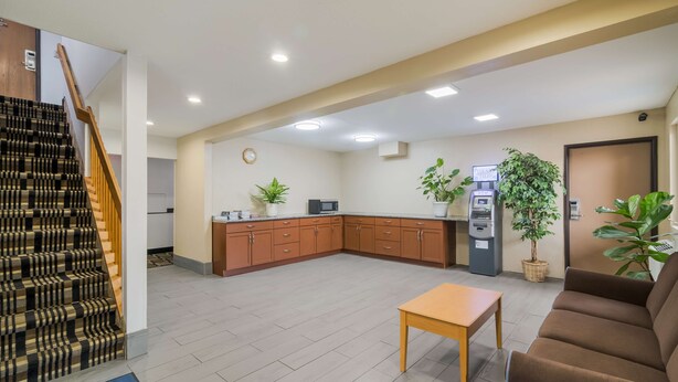 A spacious living area with a staircase, a kitchen, a sofa, and a table. - Americas Best Value Inn Fargo (Fargo)