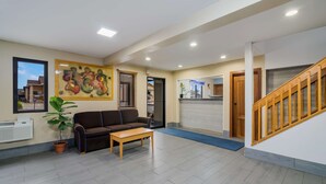 A reception area with a sofa, a coffee table, a potted plant, and a painting on the wall. - Americas Best Value Inn Fargo (Fargo)