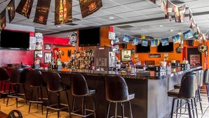 Una zona de bar con mostrador, varios taburetes y diversas pancartas y letreros.