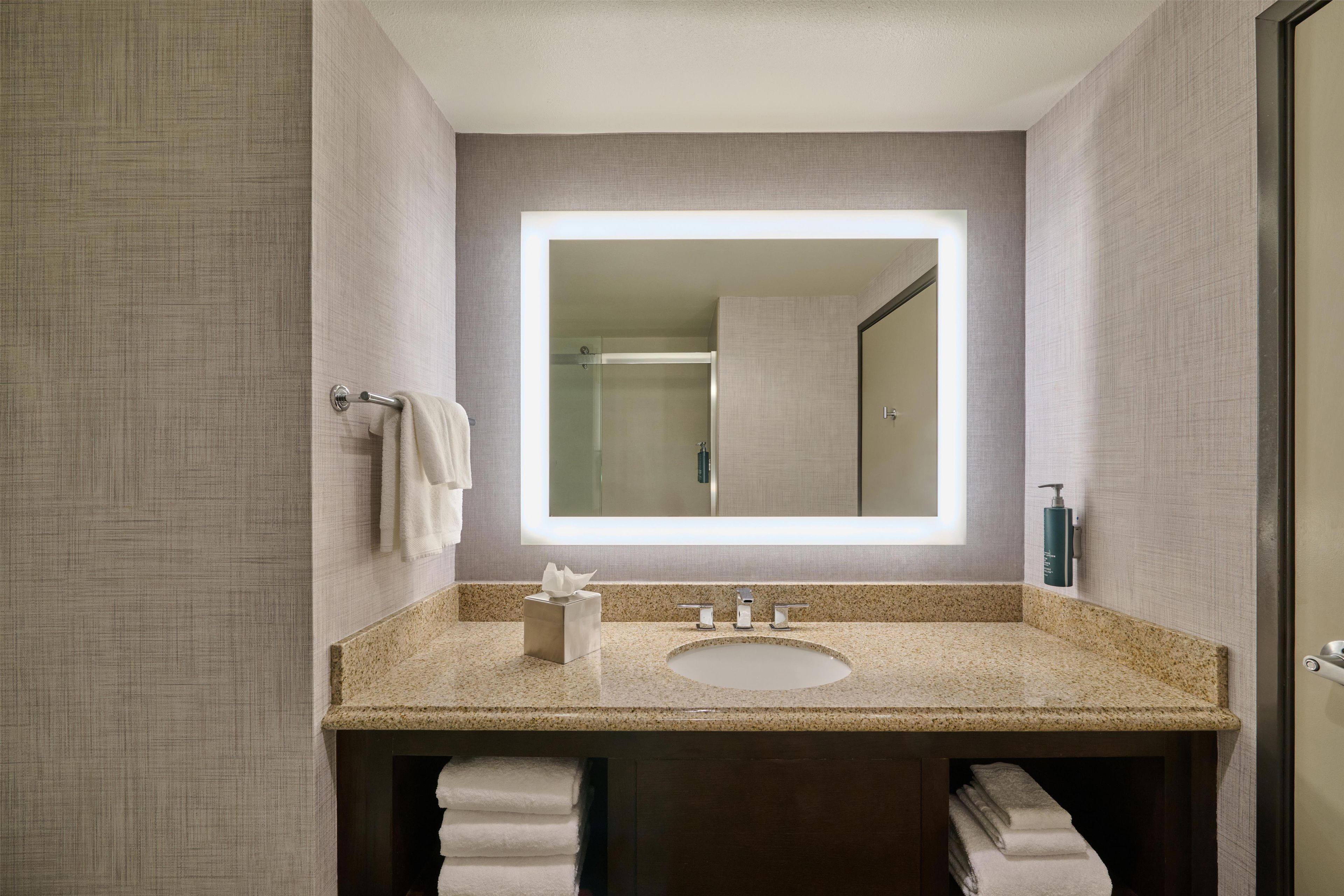 A modern bathroom with a granite countertop, a large mirror, and a built-in sink.