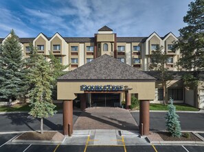 A hotel entrance with a sign reading 'DOUBLETREE by Hilton,' surrounded by trees and a parking lot.