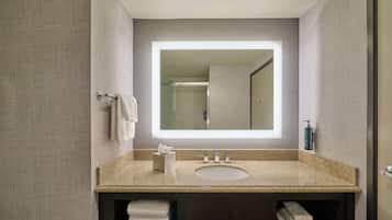 Un baño moderno con encimera de granito, un espejo grande y un lavabo empotrado.