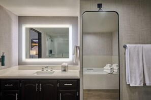 A modern bathroom with a large mirror, a sink, dark cabinets, and a shower area. - DoubleTree by Hilton Hotel Flagstaff (Flagstaff)