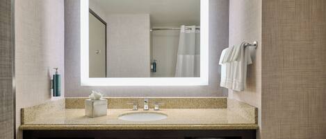 A bathroom with a large mirror, a sink, and a towel rack.
