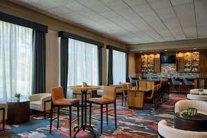 A hotel lobby with a bar area, seating arrangements, and a large window with curtains. - DoubleTree by Hilton Hotel Flagstaff (Flagstaff)