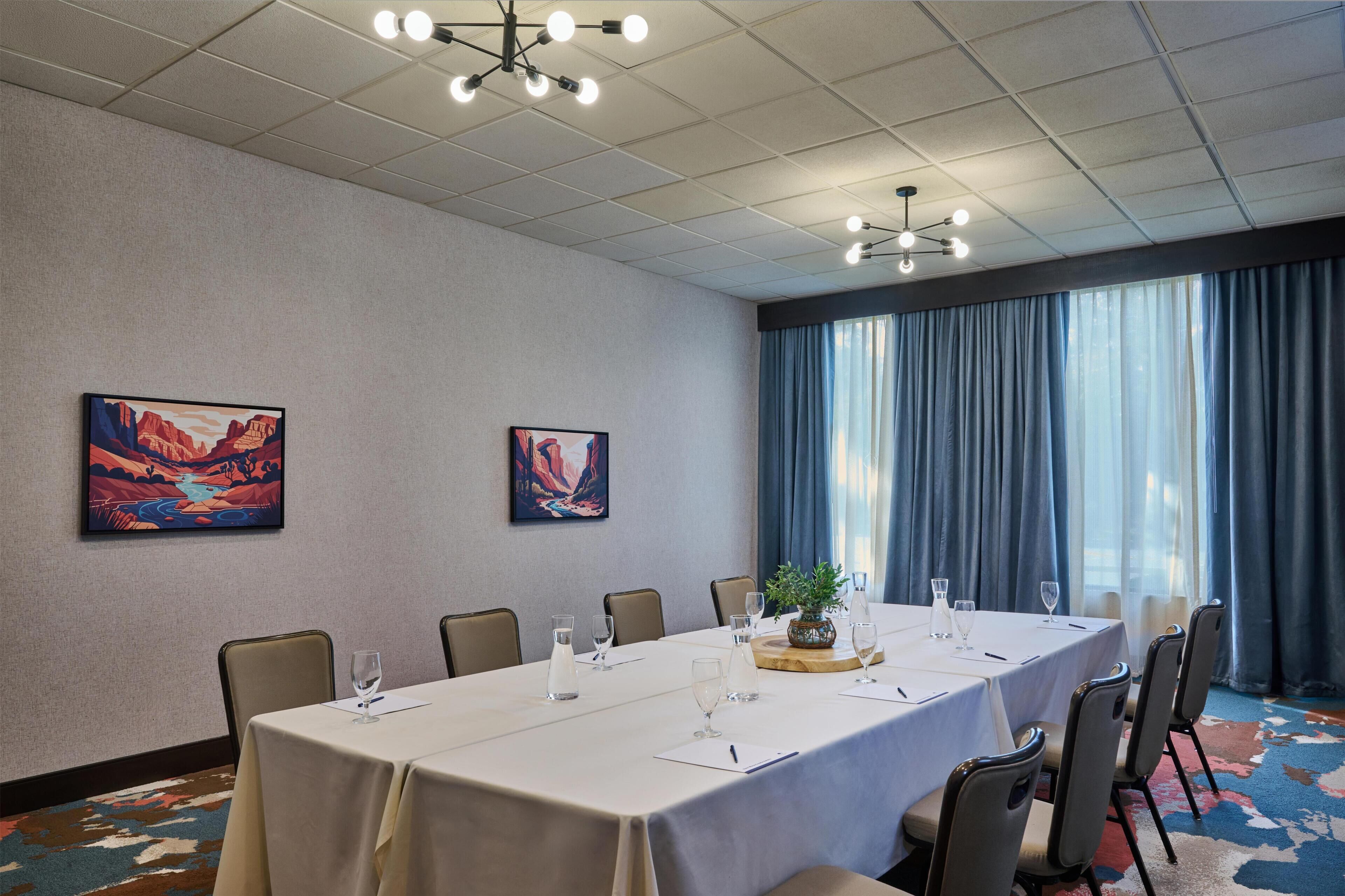 Ett konferensrum med ett långt bord, stolar och konstverk på väggarna.