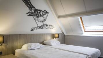 A hotel room with a bed, two bedside lamps, a wall-mounted light, and a skylight.