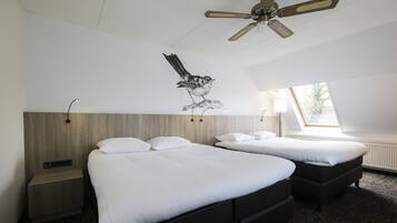Quarto de hotel com duas camas, um ventilador de teto, janela com vista e uma obra de arte na parede com a imagem de um pássaro.