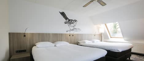 A hotel room with two beds, a ceiling fan, a window with a view, and a wall-mounted artwork of a bird.