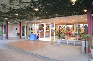 L’entrée d’un hôtel avec une façade en verre, des plantes en pot et une couronne de Noël.