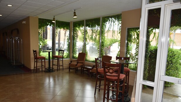 Un restaurant doté d’une terrasse avec des places assises en plein air, un sol carrelé et de grandes fenêtres donnant sur un espace verdoyant.