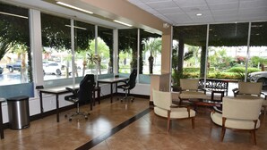 Un espace d’accueil comprenant un comptoir, des chaises et de grandes fenêtres donnant sur un parking.