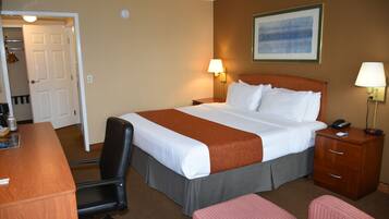 A hotel room with a bed, desk, chair, and bedside table.