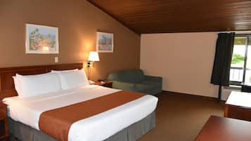 Habitación de hotel con una cama grande, un escritorio, una silla y dos lámparas fijadas a la pared.