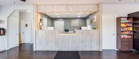 A reception area with a wooden counter, ceiling fans, and a snack shelf.