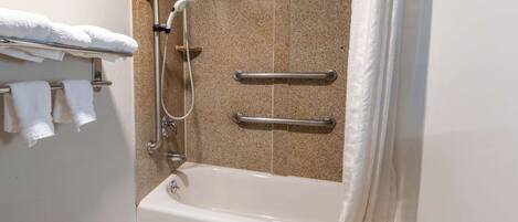 A bathroom with a bathtub, grab bars, and a towel rack.