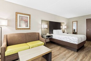 A hotel room with a bed, a sofa, a bedside table, a lamp, a framed picture, and a mirror. - Best Western Fayetteville Inn (Fayetteville)