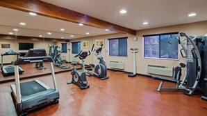 Un gimnasio con cintas de correr, bicicletas estáticas y una máquina de remo.