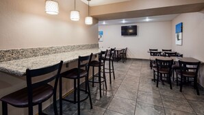 Un restaurante con mostrador de granito, sillas negras e iluminación colgante.