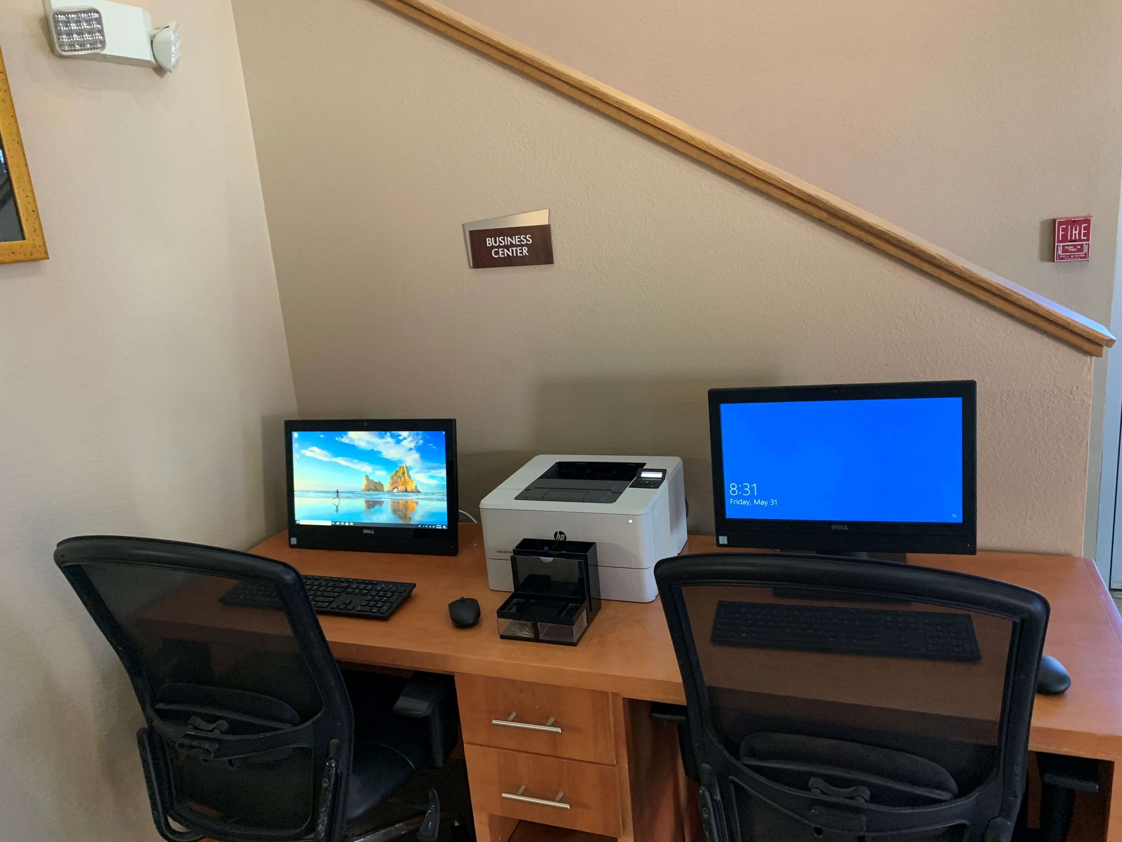 A business center desk with two monitors, a printer, and a keyboard.