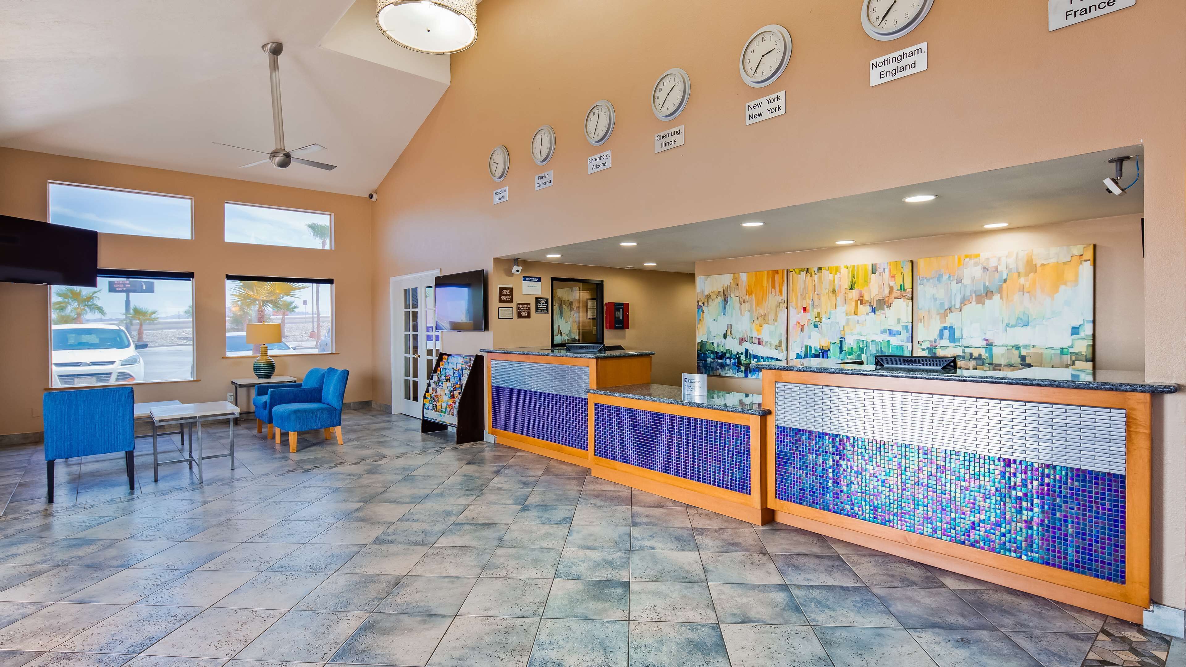 A lobby with a reception desk, seating area, and wall clocks indicating different time zones.