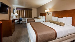 Habitación de hotel con una cama grande, un escritorio, una silla, un televisor y una ventana con cortinas.