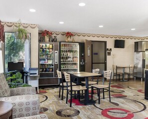 A hotel lobby with a dining area, vending machines, a refrigerator, and a television on the wall. - Econo Lodge Grand Forks near University (Grand Forks)