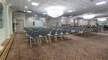 Una sala de conferències amb files de cadires, una pissarra i un penjallum.