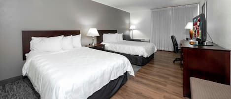 Una habitación de hotel con dos camas, un escritorio con televisor y una silla.