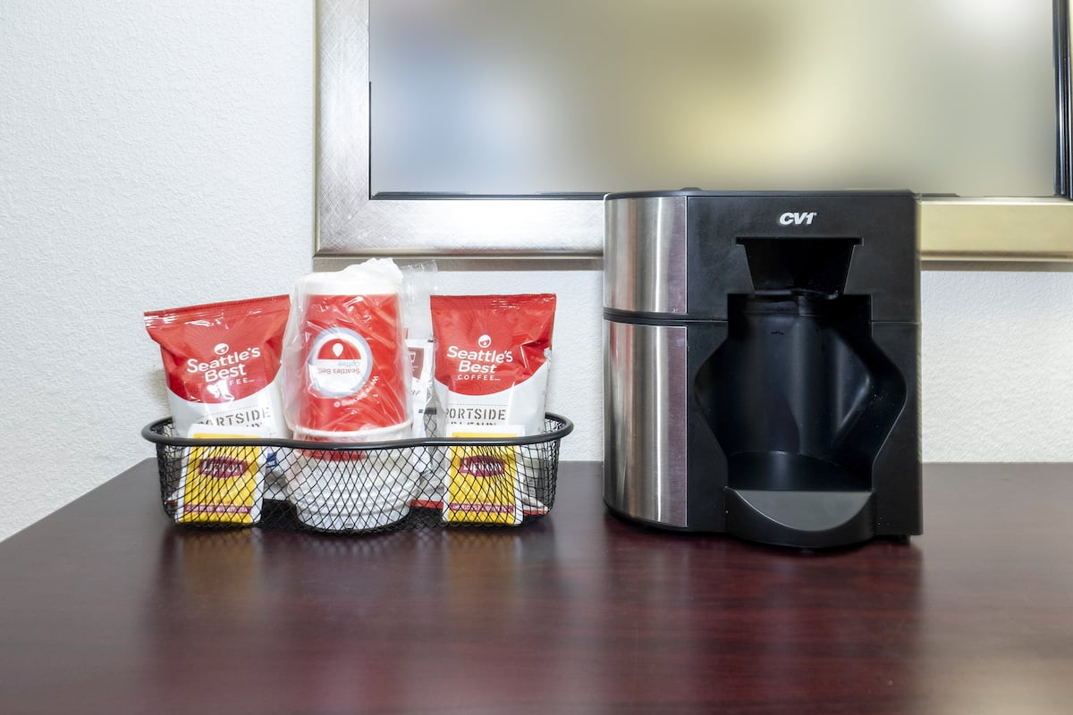 A coffee maker and a basket with coffee pods on a wooden table.