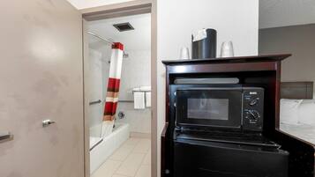 Ein kleines Hotelzimmer mit Dusche, Mikrowelle und einem Bett.
